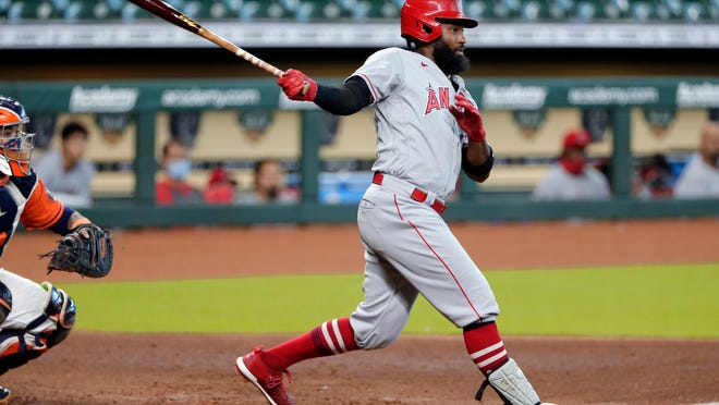 Los Angeles Angels right fielder Brian Goodwin, right, watches his one run double in front of Houston Astros catcher Martin Maldonado, left, during the inning of the first game of a doubleheader baseball game Tuesday, Aug. 25, 2020, in Houston. (AP Photo/Michael Wyke)