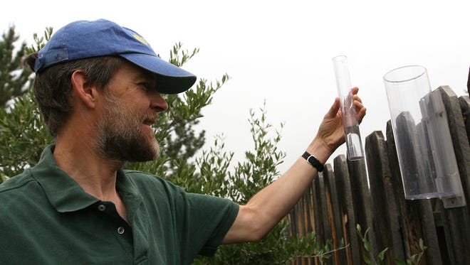 Doug Swartz checks his rain gauge for the Community Collaborative Rain, Hail and Snow Network at his home in northeast Fort Collins on the morning of Thursday, June 3, 2008.
