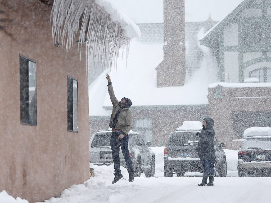Taran DePaola grabs an icicle while Isabella Dishong watches in Flagstaff, Ariz. on Jan. 22, 2017. Another winter storm is expected to drop more snow in northern Arizona and bring rain and colder temperatures to the Phoenix metro area.