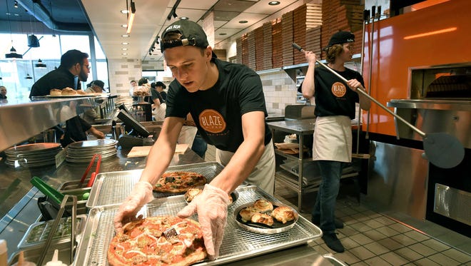 Blaze Pizza Reno employee Max Lewis reaches for a freshly baked pizza to slice up for a customer at the new pizza restaurant, where you can build your own pizza.