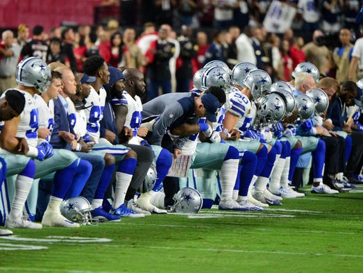 Cowboys players, coaches and staff take a knee prior