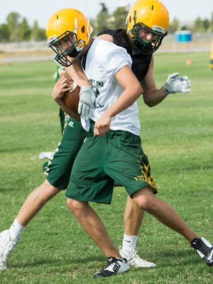 Mayfield High School football players Gaven Swinson, back, tries to take the ball out of Matthew Armendarez’s hands during strip drill, August 1, 2016, on the first official day of high school football practice in NM.