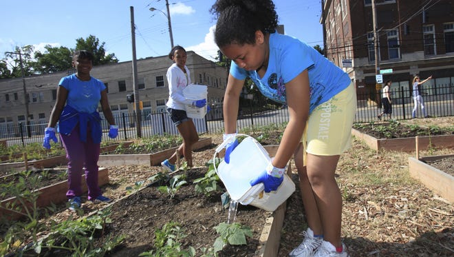 Tiondra Poyntz, 12, right, waters cucumber plants in the Parkland Community Garden at 28th and Dumesnil streets. June 13, 2013