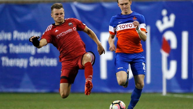FC Cincinnati's Jimmy McLaughlin (20) takes the ball down field before being tackled from behind by Ottawa midfielder Jonathon Barden (2) in the second half of the USL soccer match between FC Cincinnati and the Ottawa Fury at Nippert Stadium in Cincinnati on Wednesday, Aug. 23, 2017. FC Cincinnati secured a 3-1 win over Ottawa before more than 20,000 fans.