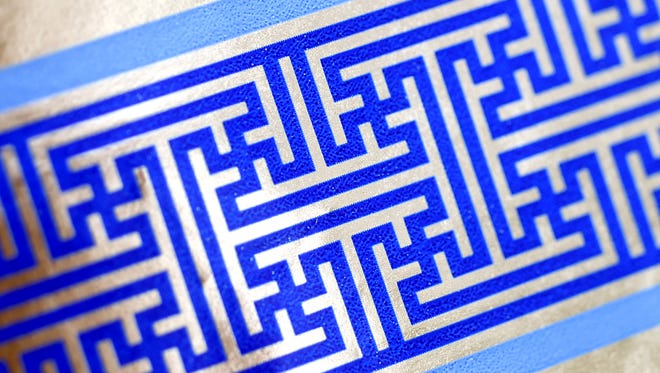 Cheryl Shapiro displays the Hanukkah gift wrap with a swastika-like pattern she found at Walgreens in Northridge, Calif., Monday,  Dec. 8, 2014.  The wrapping paper has been recalled from stores nationwide.