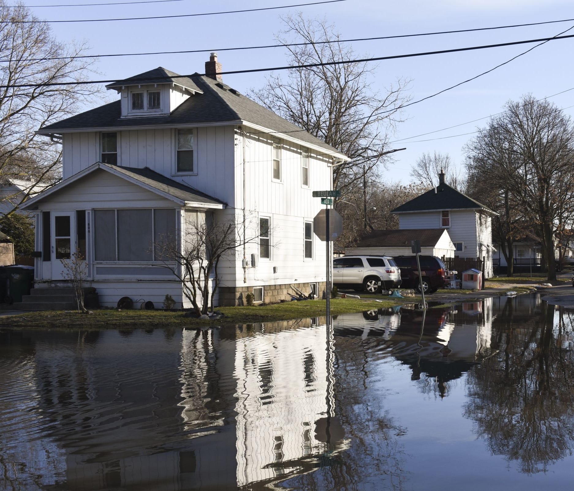 In this Thursday, Feb. 22, 2018 photo, the intersection of Ada and Beulah Streets is flooded in the Baker-Donora neighborhood in Lansing, Mich. Flooding that prompted evacuations in parts of the Midwest persisted Friday in Michigan, Indiana, and Ohio