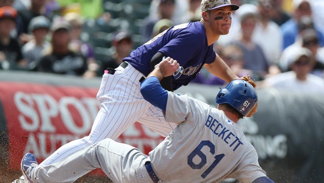 The Dodgers' Josh Beckett may have hurt his hip on this slide into third base Sunday as Rockies third baseman Nolan Arenado fields the throw.