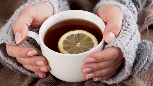 A lady's hands holding a cup of tea with a whole...