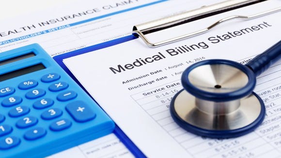 A Medical Billing Statement on a blue clipboard, next to a blue calculator, with a blue stethoscope sitting on top of it.