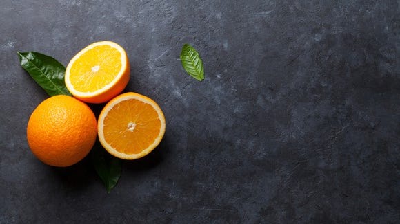 Three sliced oranges on a dark gray surface.