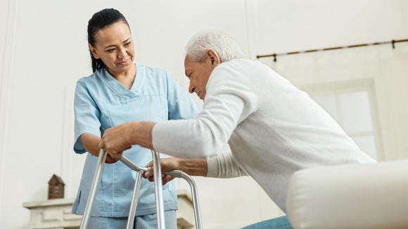 Nurse assisting an elderly patient in standing up.