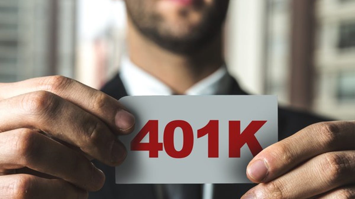 Man holding a small sign spelling out "401K" in red letters.