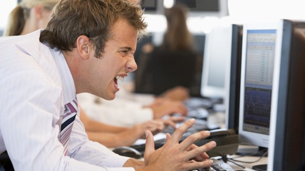 A visibly angry and frustrated investor looking at losses on his computer monitor.