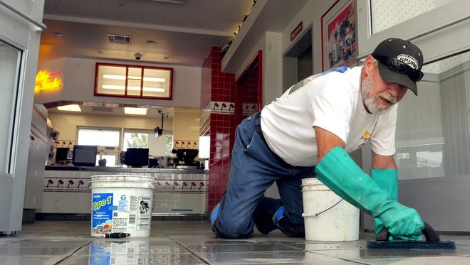Gary McChesney finishes-up the floor tiles on the entrance to Medford's In-N-Out restaurant Wednesday, Aug. 26, 2015 in Medford, Ore.