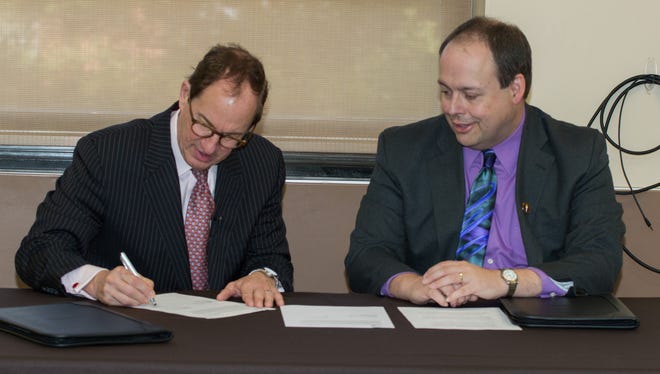 Dean Rod Smolla, left, signs the articulation agreement beside Rowan University Provost James Newell.