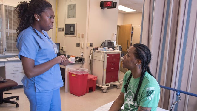 Registered nurse Tyra Hickman chats with Robert Melton, who was diagnosed with sickle cell disease as an infant, during a clinic visit.