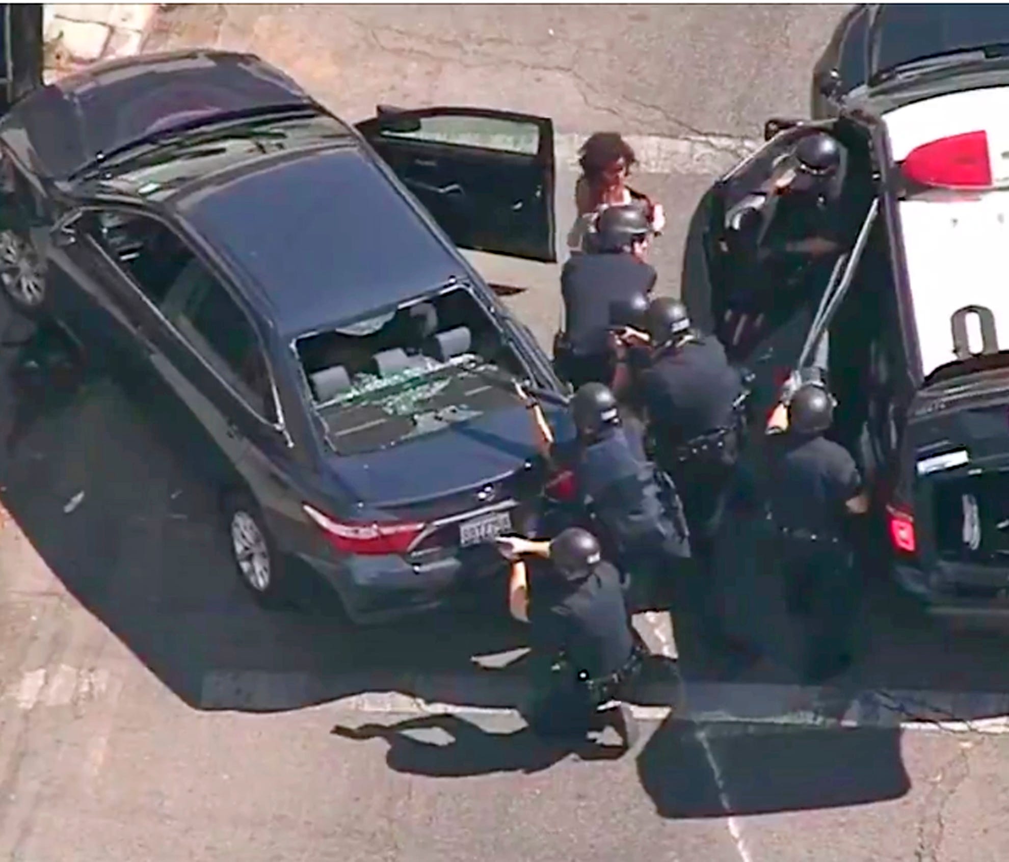 In this image from video provided by KNBC-TV, Los Angeles Police officers remove a passenger from a car that crashed after a pursuit with the driver who ran into a nearby Trader Joe's supermarket in the Silver Lake district of Los Angeles Saturday, J