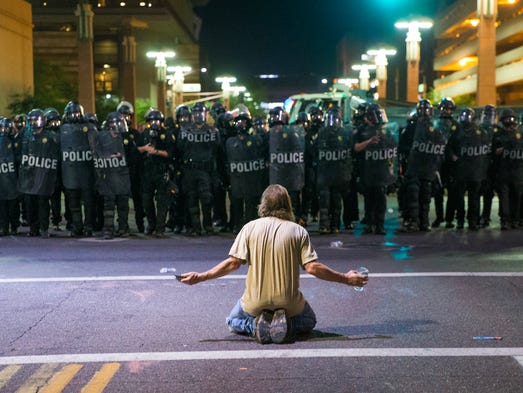 A protester sits on Second Street in front of a line