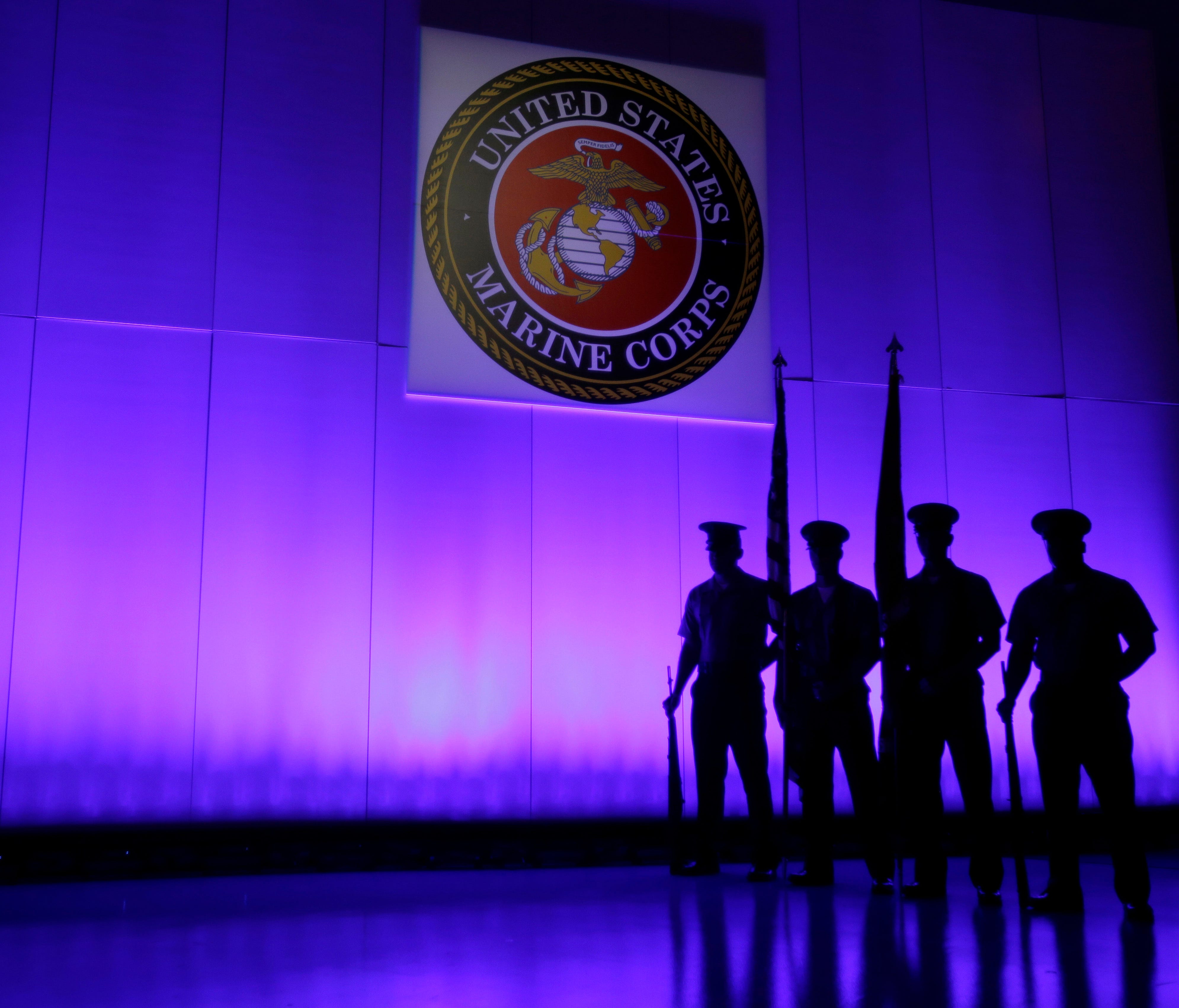 FILE- In this May 5, 2014, file photo, a U.S. Marine Corps Color Guard stands under a Marine Corps emblem in Jupiter, Fla. The Defense Department is investigating reports that some Marines shared naked photographs of female Marines, veterans and othe