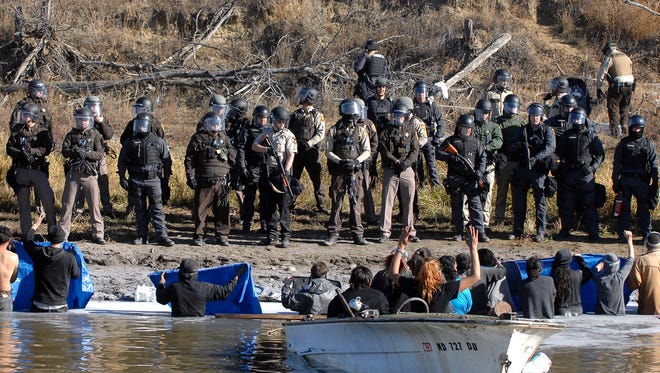Dakota Access Pipeline protesters stand waist deep in the Cantapeta Creek, northeast of the Oceti Sakowin Camp, near Cannon Ball, N.D., Wednesday, Nov. 2, 2016. Officers in riot gear clashed again Wednesday with protesters near the Dakota Access pipeline, hitting dozens with pepper spray as they waded through waist-deep water in an attempt to reach property owned by the pipeline's developer. (Mike Mccleary/The Bismarck Tribune via AP)