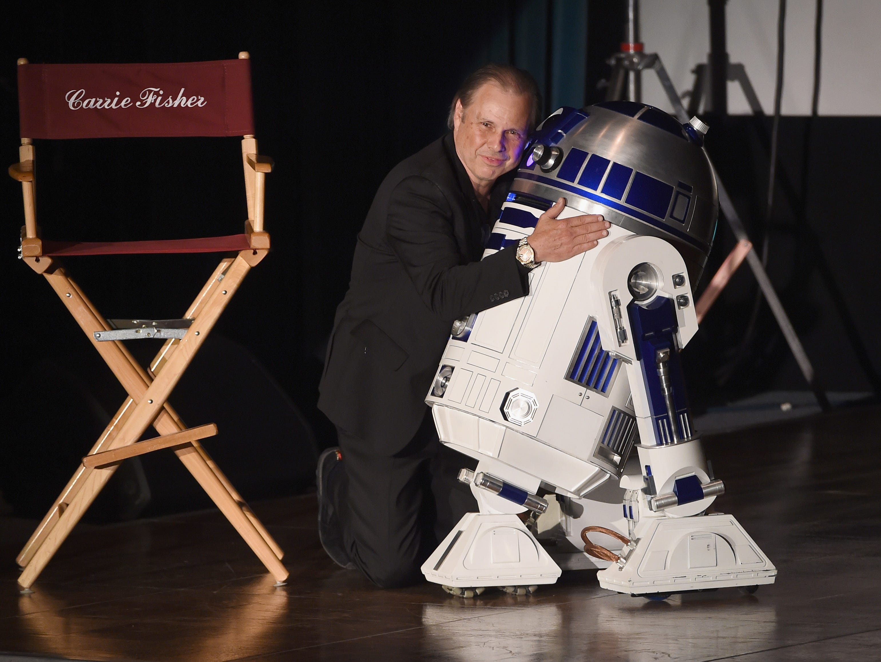 Todd Fisher comforts a mournful R2-D2 at the memorial service for Carrie Fisher and Debbie Reynolds.