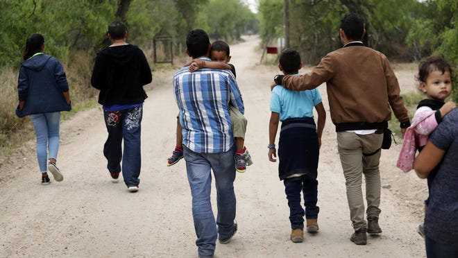 In this March 14, 2019, file photo, a group of migrant families walk from the Rio Grande, the river separating the U.S. and Mexico in Texas, near McAllen, Texas, right before being apprehended by Border Patrol.