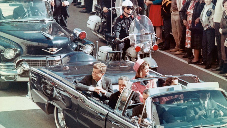 President and Mrs. John F. Kennedy smile at the crowds lining their motorcade route in Dallas on November 22, 1963, moments before the shooting.