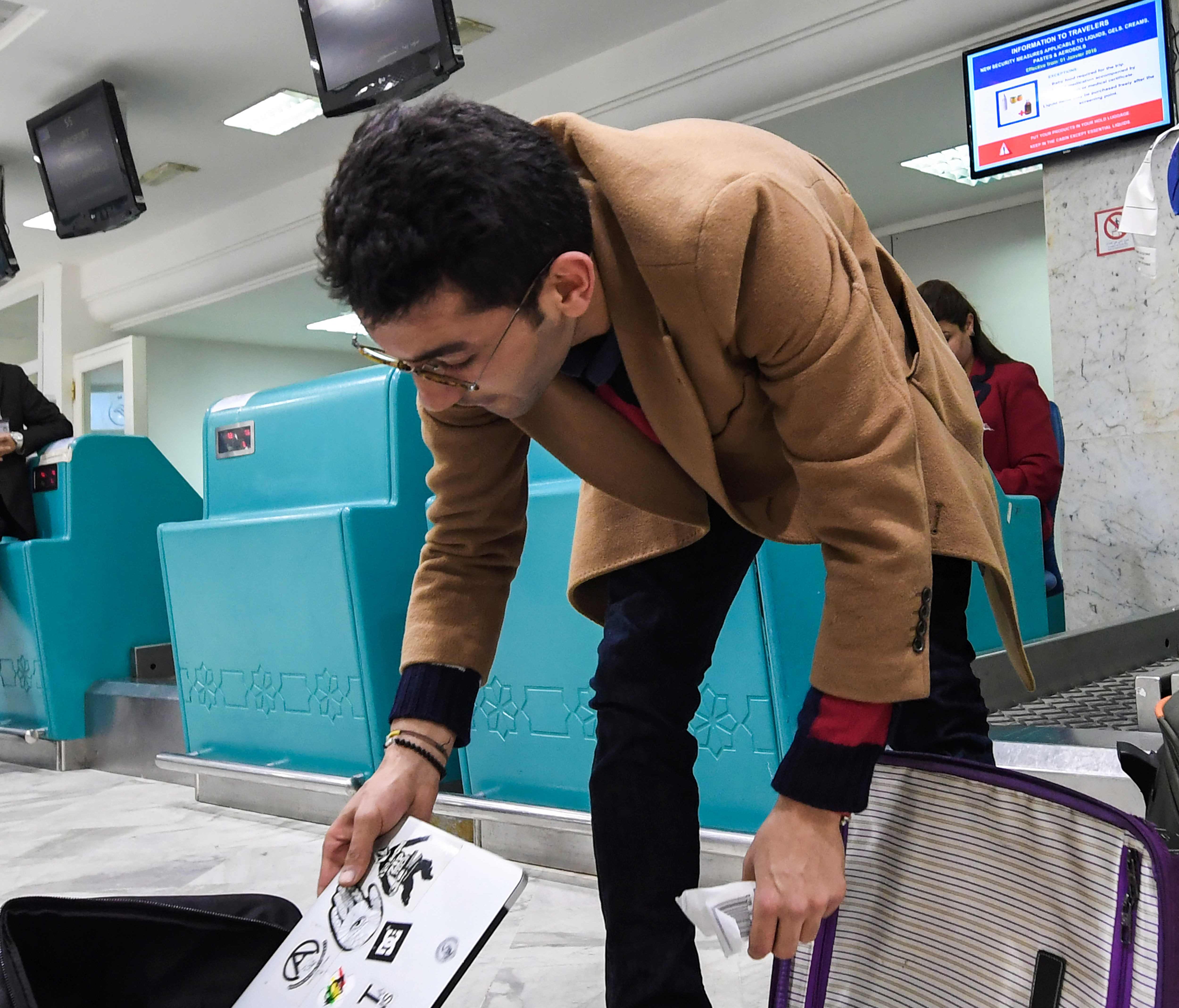 A Libyan traveller packs his laptop in his suitcase before boarding his flight for London from Tunisia.