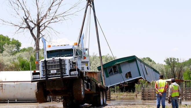 A winch truck pulls a water-logged mobile home from the San Juan River off County Road 5008 Wednesday.