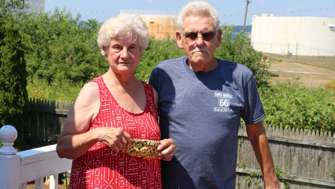 The Island Fuel tank farm serves as a backdrop as Carlos and Mary Lou Amaral stand on the back deck of their Foot Street home in Tiverton. The Amarals are concerned about a proposal that would add two 45,000-gallon propane tanks to the property.