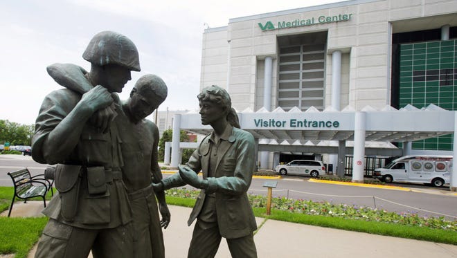 Three statues portraying a wounded soldier being helped stand on the grounds of the Minneapolis VA hospital.