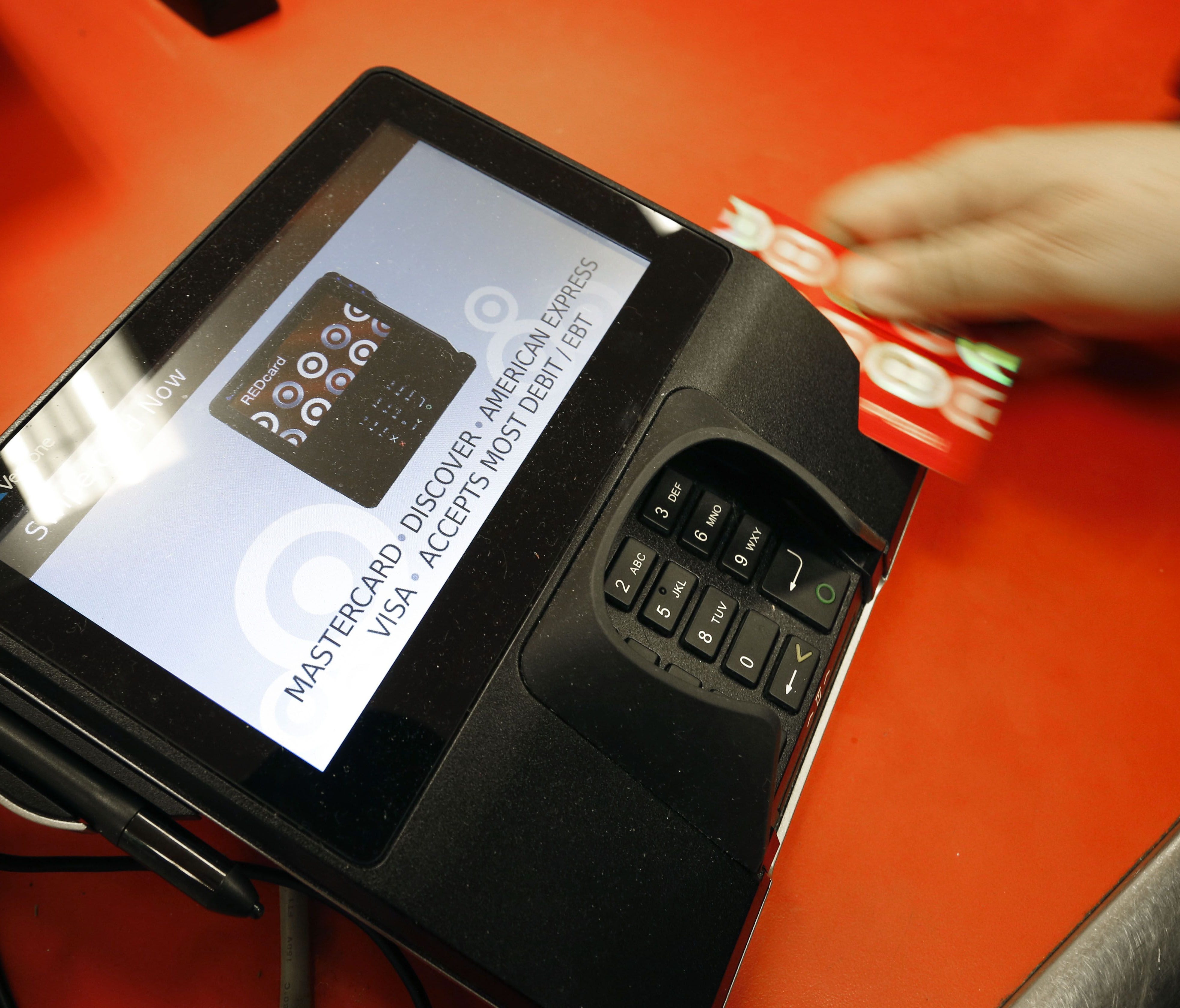 In this Friday, Nov. 28, 2014 file photo, a shopper pays for her purchases at a Target store in South Portland, Maine. Criminals stole personal information from tens of millions of Americans in data breaches in 2014. Of those affected, one in three b