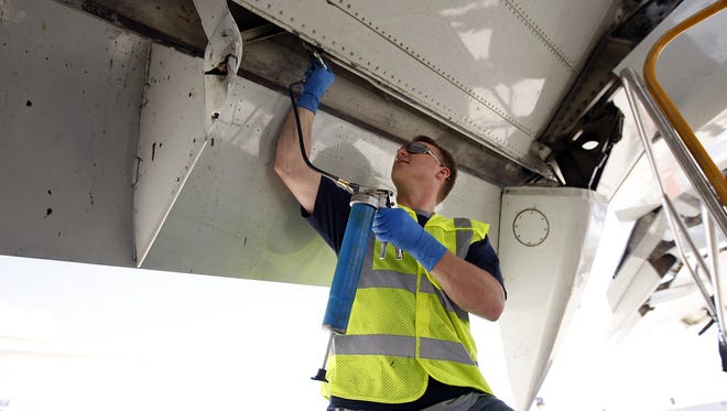 An aircraft mechanic for Air Transport Services Group lubricates the flaps of a Boeing 767 at ATSG's facility in Wilmington. ATSG will use 767s in flying cargo for Amazon under a new five-year deal.