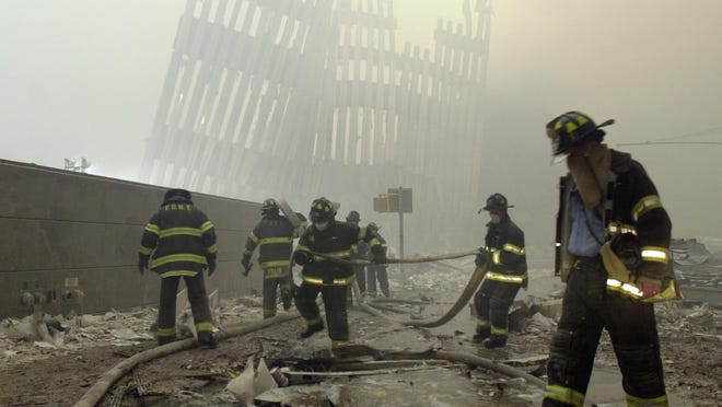 In this Sept. 11, 2001, file photo, firefighters work beneath the destroyed mullions, the vertical struts that once faced the outer walls of the World Trade Center towers, after a terrorist attack on the twin towers in New York.