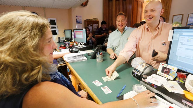 
Dan Peo smiles as he hands Deputy Clerk Brooke Wagoner a $20 bill to pay for his and partner Douglas Taylor’s Tippecanoe County marriage license. 
