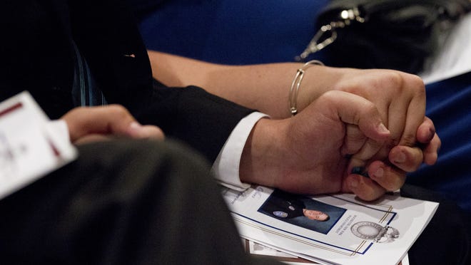 
Family members of Officer Daryl Pierson hold hands during his funeral at Blue Cross Arena on Sept. 10.
