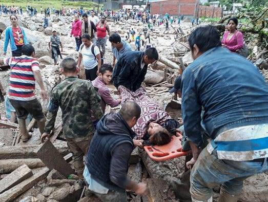 People help carry an injured woman after mudslides