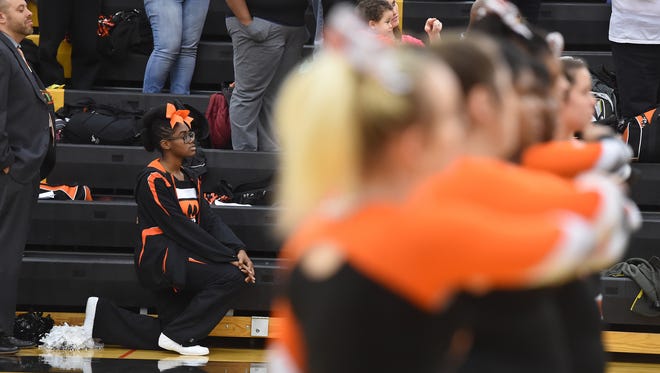Northeastern cheerleader Ajani Powell takes a knee during the National Anthem before the boys basketball team takes on Red Lion in Red Lion on Tuesday, Dec. 13, 2016. 