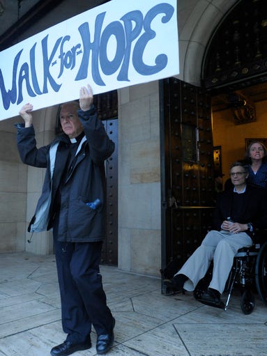 The Rev. Robert Scullin carries a sign stating, "Walk