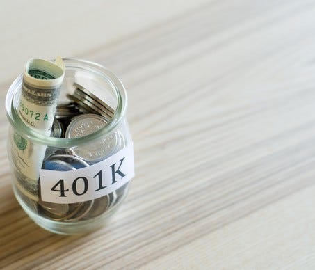 Glass jar with rolled-up bills and coins labeled 401K