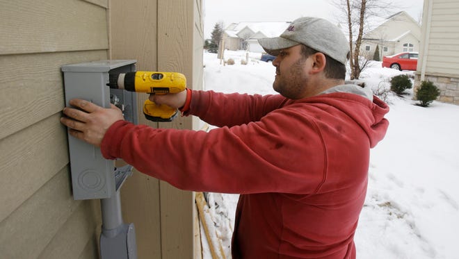 In this Friday, Jan. 10, 2014, photo, Paquale Cocca installs a new electrical box on a new home, in Pepper Pike, Ohio.