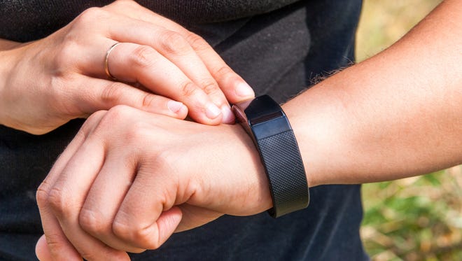 Girl checks the information on the screen of the fitness band. Hands in the picture, close-up