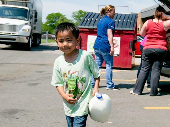 Jayden Hang, 5, of Warren carries milk to his car at