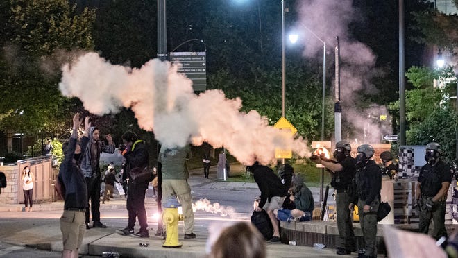 Fireworks explode as police shoot tear gas and rubber bullets at protestors during a second night of protesting in downtown Asheville in response to the killing of George Floyd, who is black, by a white police officer in Minneapolis on June 1, 2020.