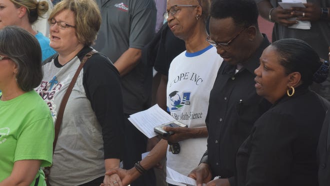 Christie Coulon (far left) and Stella Poindexter hold hands while singing "Amazing Grace" at a prayer vigil held Monday evening on the front steps of the Rapides Parish Courthouse. Pastor Huey Long (third from right) and his wife, Shirley Long, also attended the vigil.