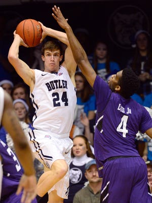 Butler Bulldogs guard Kellen Dunham (24) jumps up to pass the ball around Northwestern Wildcats forward Vic Law (4) during the second half of the game at Hinkle Fieldhouse. Butler Bulldogs defeat Northwestern Wildcats 65 to 56.