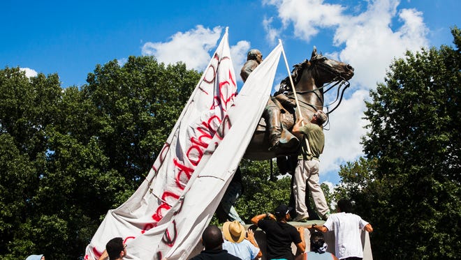 Activist Bill Stegall attempts to cover Nathan Bedford Forrest's Confederate statue during #TakeEmDown901's "Rally for Removal! Solidarity with Charlottesville!" action Aug. 19, 2017, at Health Sciences Park. Moments later, chaos erupted, leading several demonstrators to be arrested by the Memphis Police Department.
