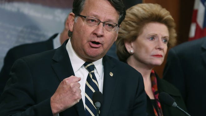 Rep. Gary Peters (D-MI) is flanked by Sen. Debbie Stabenow (D-MI), while speaking about help for the families affected in Flint water crisis, during a news conference on Capitol Hill, January 28, 2016 in Washington, DC.
