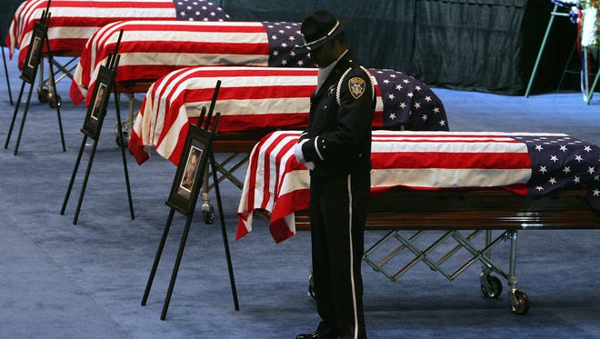 A member of Oakland Police Honor Guard stands at his post near the four caskets of Oakland Police Officers Sgt. Mark Dunakin, 40; John Hege, 41; Sgt. Ervin Romans, 43; and Sgt. Daniel Sakai, 35, during a funeral  at Oracle Arena in Oakland, Calif.