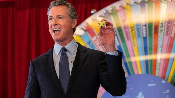 California Gov. Gavin Newsom holds up a lottery ba